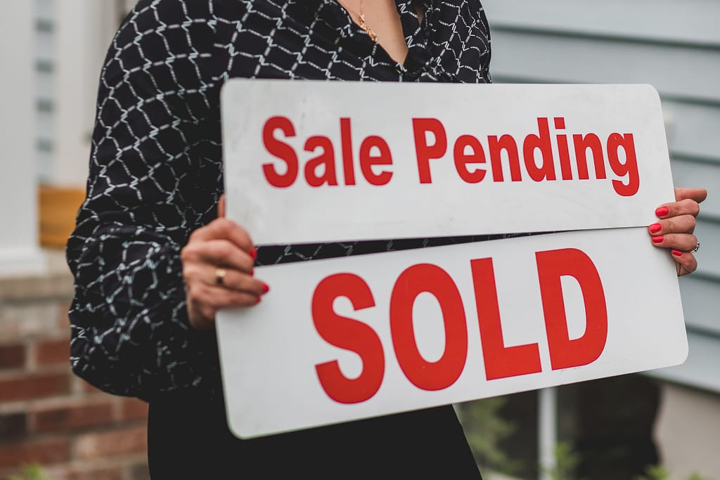 Sale Pending and Sold sign held by real estate agent.